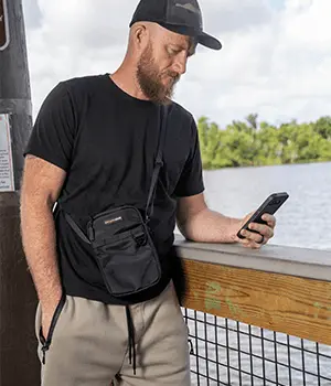 Man wearing an EscapeZone Faraday crossbody bag by the water