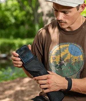 Man sealing his phone in an EscapeZone Faraday phone bag outdoors