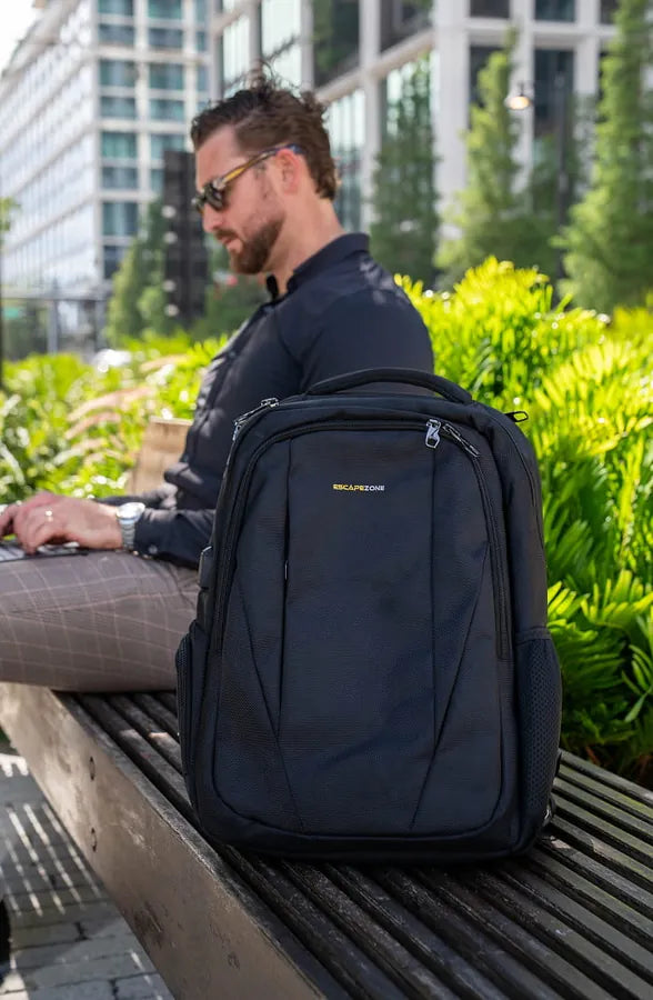 Man working on a laptop next to the EscapeZone ballistic backpack in the city